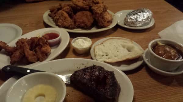 Several plates of food on a wooden table.
