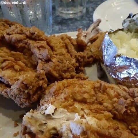 Fried chicken on a plate with a side baked potato