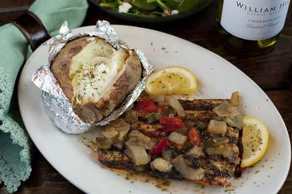 An 8 oz. filet, lightly seasoned in a vinaigrette dressing & char-grilled, then covered in sweet onions & bell peppers with a side baked potato.