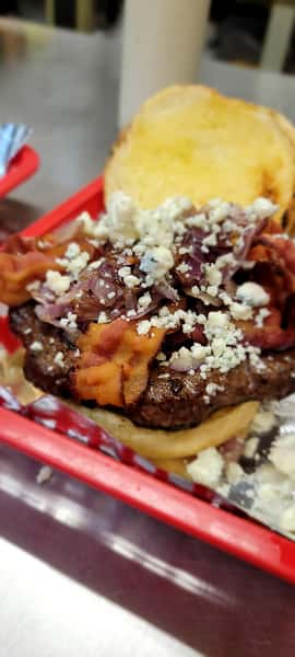 A gourmet burger topped with bacon, caramelized onions, and crumbled blue cheese.