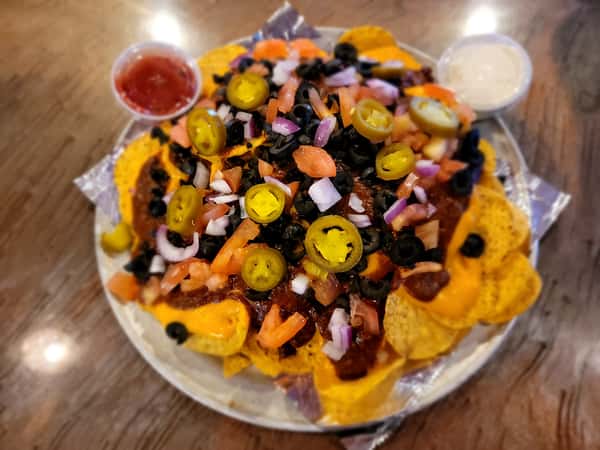 Loaded chili cheese nachos topped with jalapeños, olives, and onion, served with dipping sauces at The John Hoover Inn.
