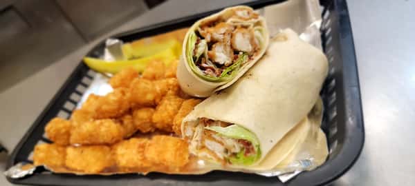 Golden tater tots and a halved fried chicken wrap served in a black basket at The John Hoover Inn.