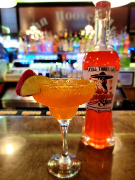Bright orange frozen margarita cocktail with lime and strawberry at The John Hoover Inn bar.