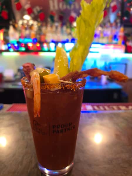 Bloody Mary mixed drink with celery and lemon garnish on a bar counter.