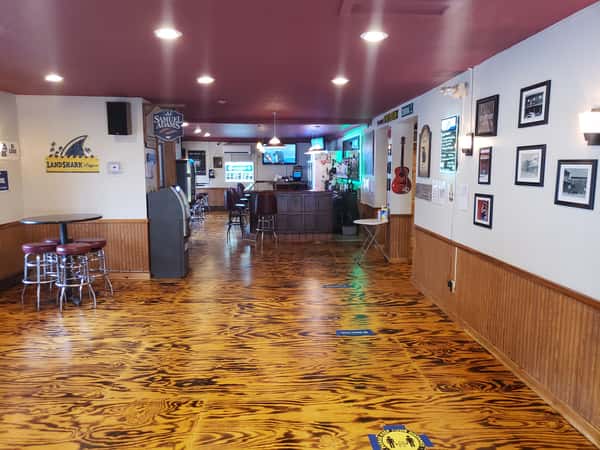 John Hoover Inn bar interior featuring a distinctive, striped wood-grain floor, maroon ceiling, and white wainscoted walls leading to the bar counter.