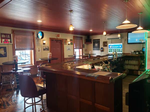 Interior view of the John Hoover Inn bar, featuring a brown wood counter, maroon ceiling, and high-top seating.