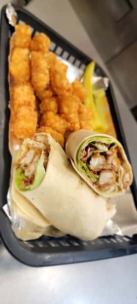 Golden tater tots and a halved fried chicken wrap served in a black basket at The John Hoover Inn.