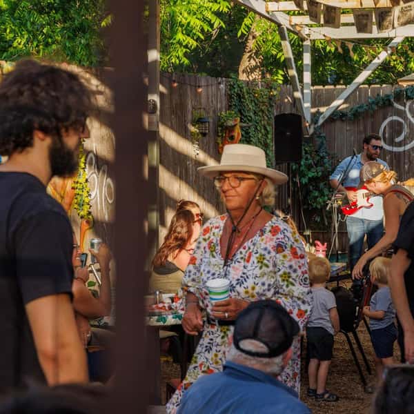 Outdoor restaurant patio with live band, guests socializing, and relaxed backyard dining atmosphere under string lights