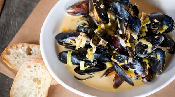 Bowl of mussels in creamy wine sauce with herbs.