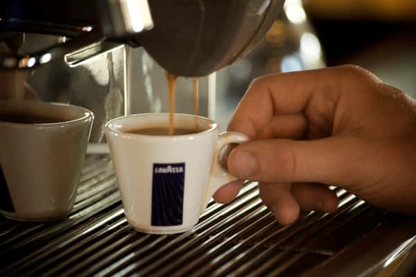 Espresso being poured into a small white cup from a coffee machine.