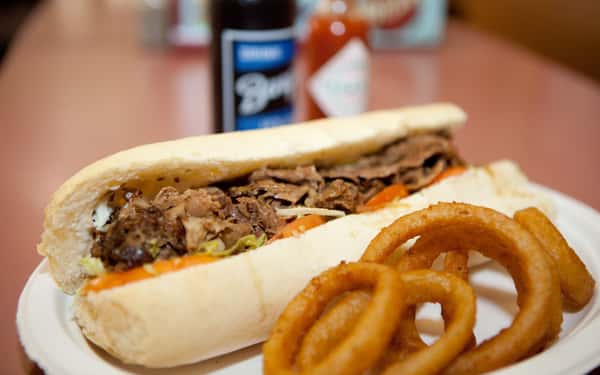 Pulled pork poboy with lettuce and tomato with onion rings