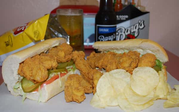 Fried shrimp poboy with lettuce, tomato and pickles and a side of potato chips