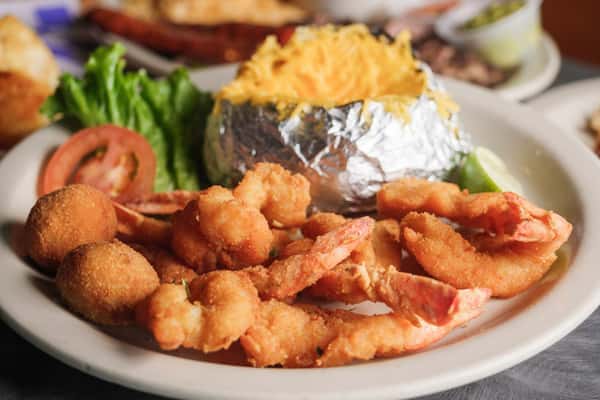 Popcorn shrimp with hush puppies, cheesy baked potato, and slice of tomato and lettuce