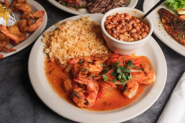 plate of shrimp, rice and baked beans with other entrees on a table