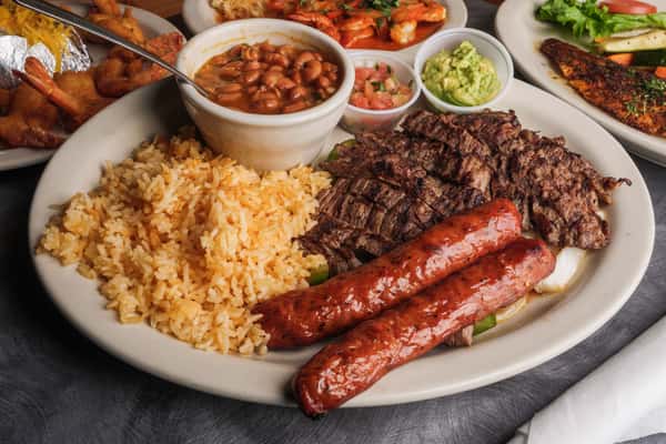 platter of rice, baked beans, beef, and sausage with cups of salsa and guacamole
