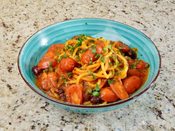 Spaghetti pasta with cherry tomatoes, olives, and fresh parsley in a tomato sauce