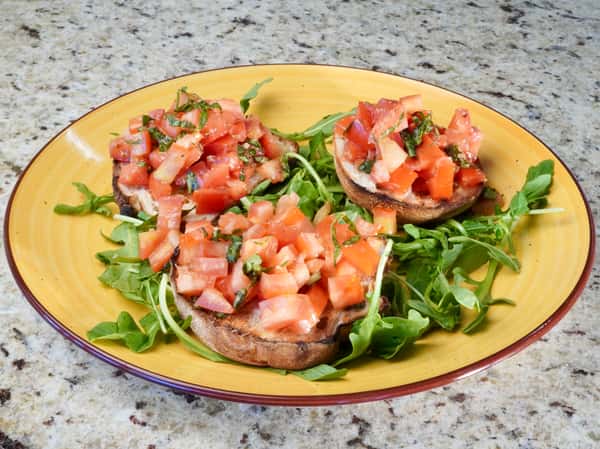 Bruschetta with diced tomatoes and fresh basil on a bed of arugula