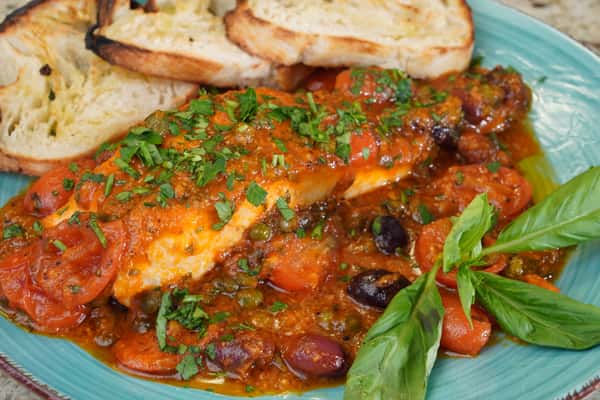 Chicken breast in tomato olive sauce with grilled bread and fresh basil