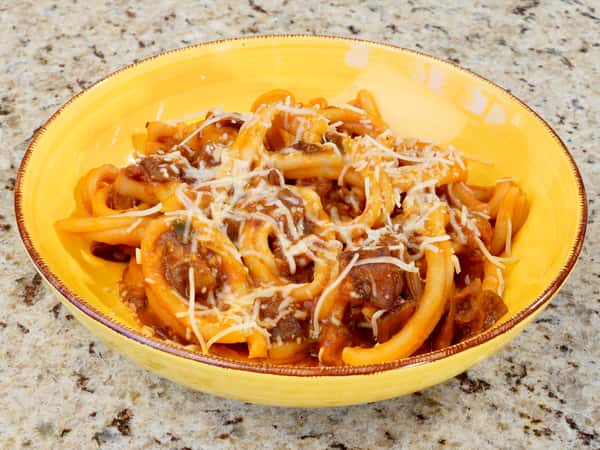 Bucatini pasta served with rich Bolognese meat sauce and grated Parmesan cheese.