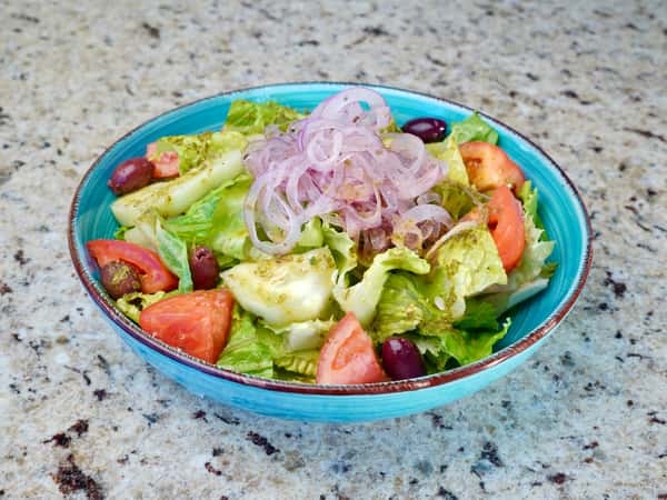 Fresh green salad with tomatoes, olives, and onions in a turquoise bowl