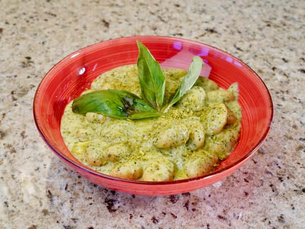 Gnocchi in creamy pesto sauce garnished with basil leaves