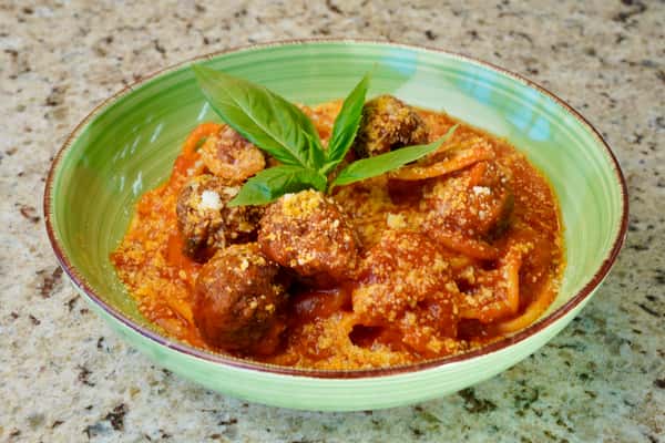 Spaghetti with meatballs in tomato sauce garnished with basil