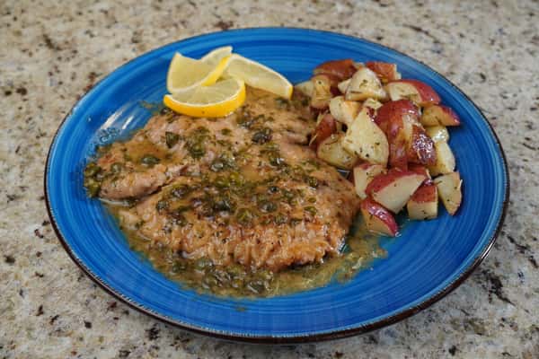 lemon chicken breast with roasted red potatoes on blue plate