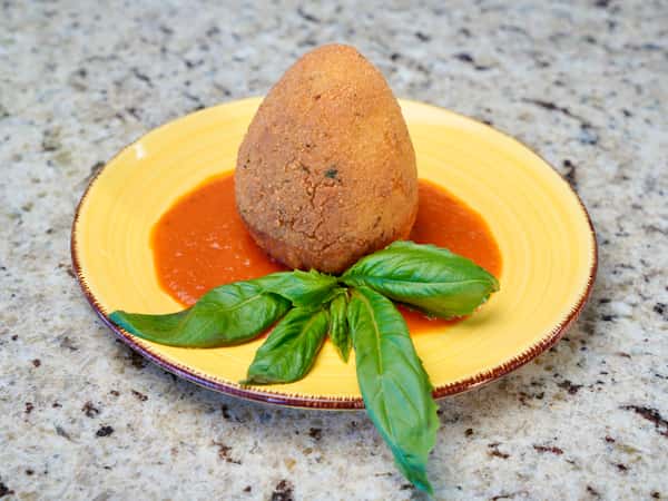 Sicilian arancini served on tomato sauce with fresh basil