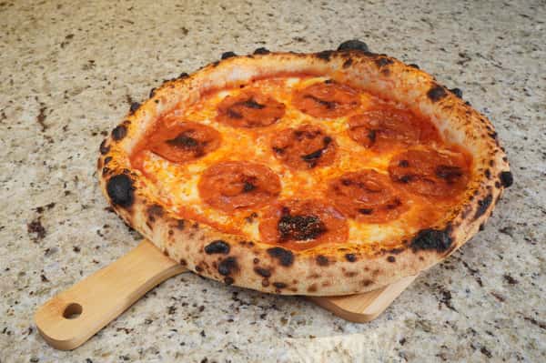 Neapolitan-style pepperoni pizza with melted cheese and charred crust