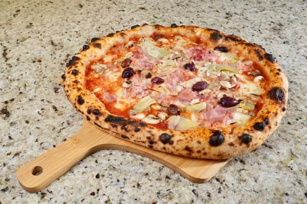 Neapolitan-style pizza with ham, black olives, mushrooms, and artichokes on a wooden peel.