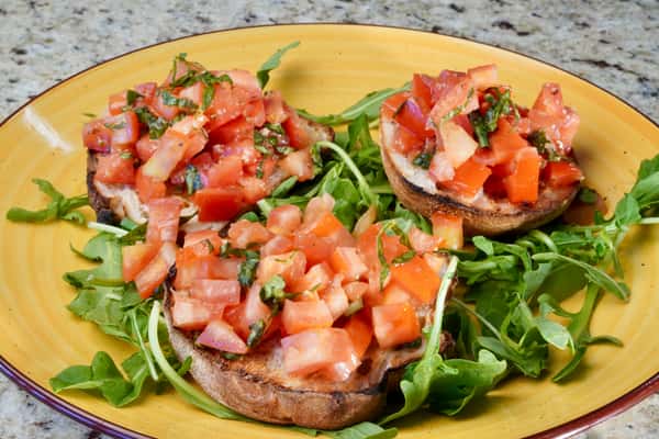 Tomato bruschetta with fresh basil on toasted bread and arugula