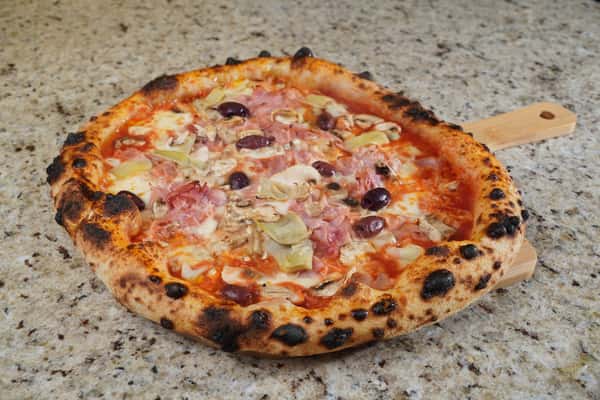 capricciosa pizza with ham, artichokes, mushrooms and olives on marble surface