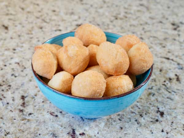Bowl of golden fried dough balls on a granite countertop