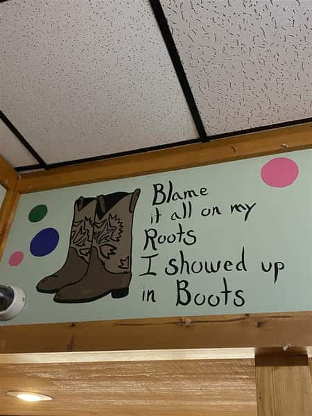 a sign in the restaurant that says "blame it all on my roots i showed up in boot"