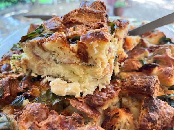 A close-up of a warm, homemade baked dessert layered with cinnamon, sugar, and flaky pastry, offering a comforting, fresh-from-the-oven look.