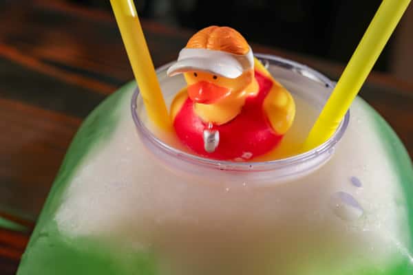 Frozen cocktail served in a large glass with a lifeguard rubber duck and two yellow straws.