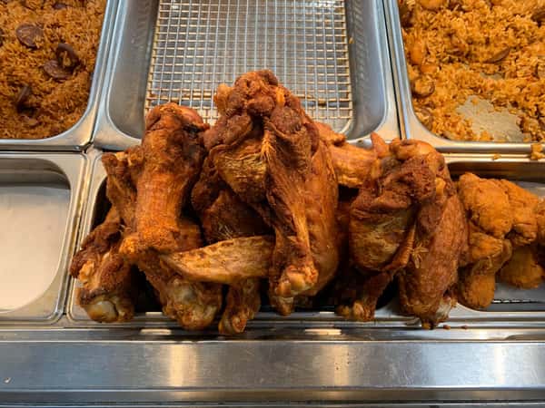 Crispy fried chicken wings and drumsticks in metal hot bin