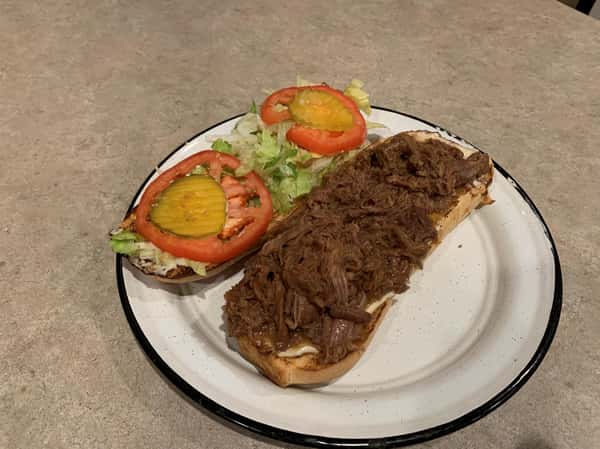 Pulled pork poboy fully dressed with lettuce tomato and mayo