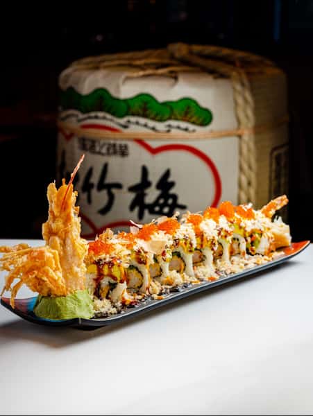 A platter of crispy tempura with a Japanese sake bottle in the background