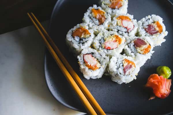 Assorted sushi rolls arranged on a dark plate with chopsticks