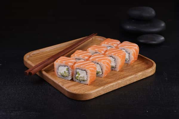 Fresh salmon sushi rolls arranged on a wooden tray