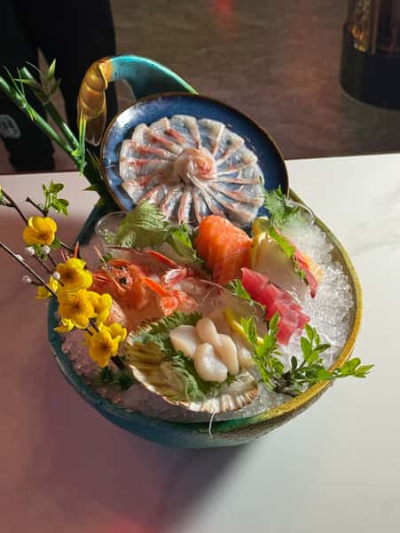 A colorful sashimi and seafood platter garnished with flowers