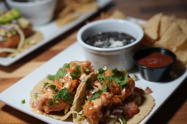 Filled up tacos with fresh garnish and sauces on the side