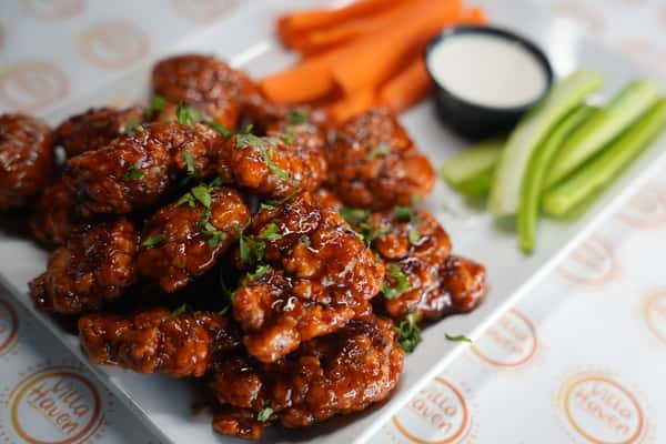 Sticky wings with a side of white sauce and vegetable sticks