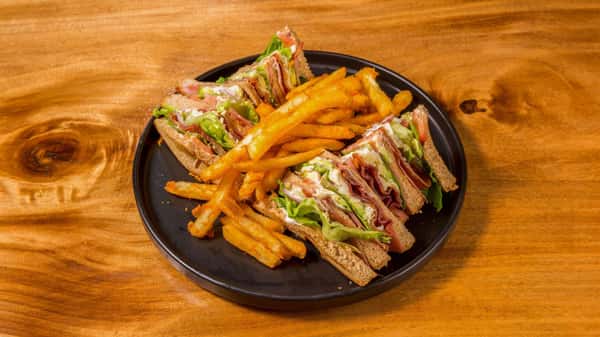 Club sandwich served with crispy fries and pickle spear.
