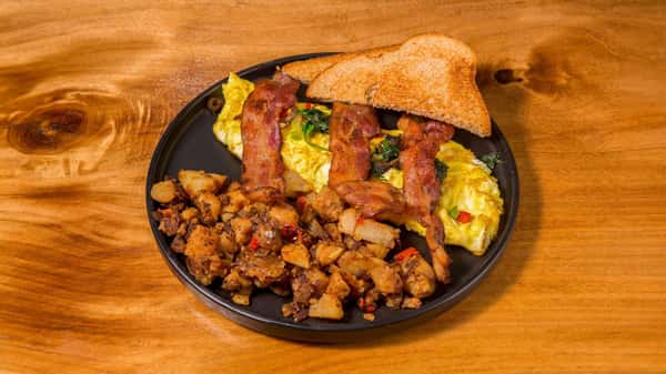 Breakfast platter with eggs, seasoned potatoes, bacon, and toast.