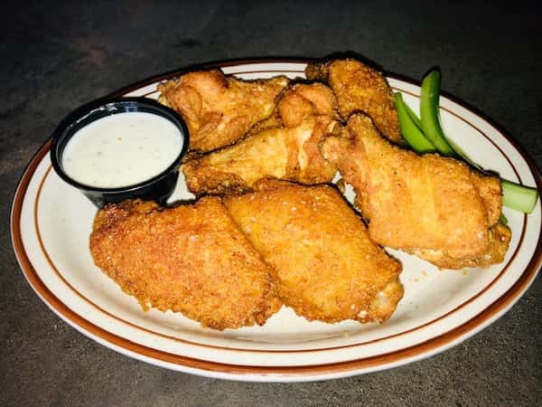 a plate of wings with ranch and celery on the side