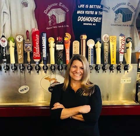 a lady smiling at the camera in front of beers on tap
