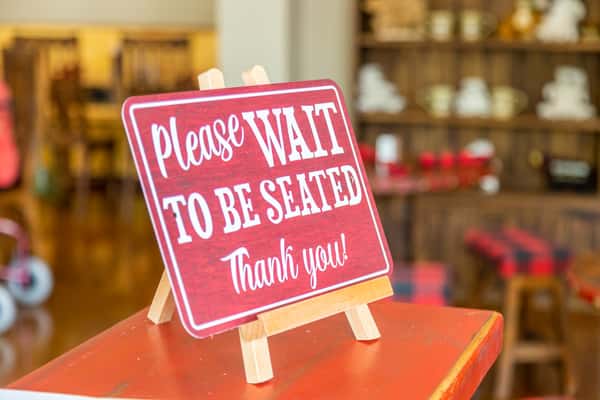 Please wait to be seated red sign