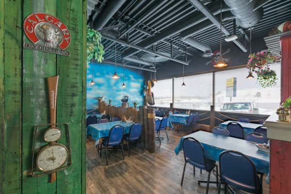Nautical-themed dining area with blue ocean mural, pelican statue, rope accents, and ocean-blue tablecloths.